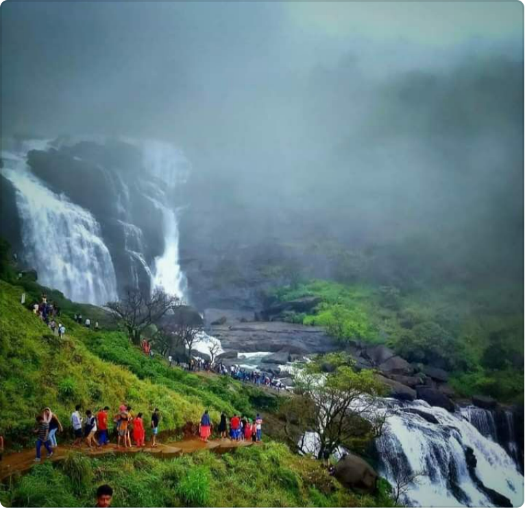 a group of people are walking towards a waterfall